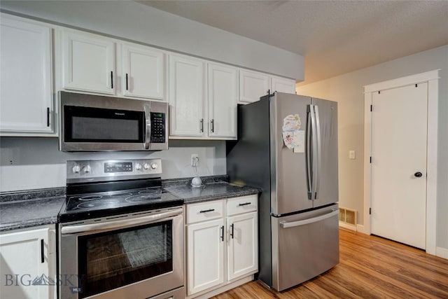 kitchen with white cabinetry, stainless steel appliances, and light hardwood / wood-style floors