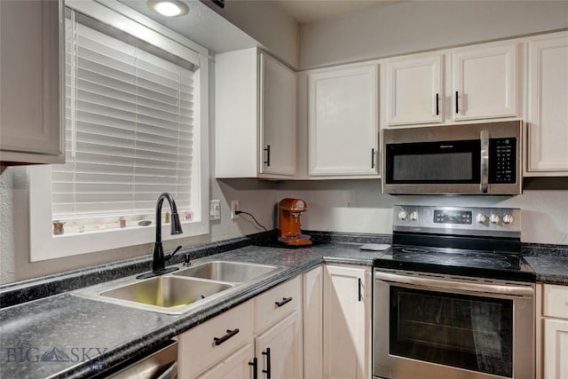 kitchen with appliances with stainless steel finishes, sink, and white cabinets