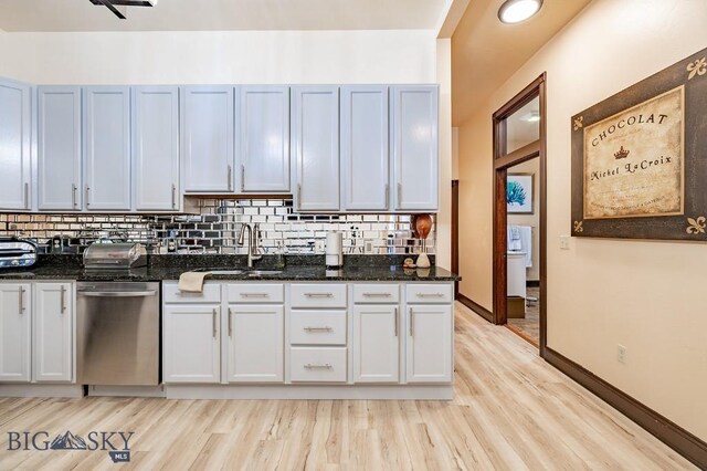 kitchen with decorative backsplash, stainless steel dishwasher, dark stone counters, and white cabinets