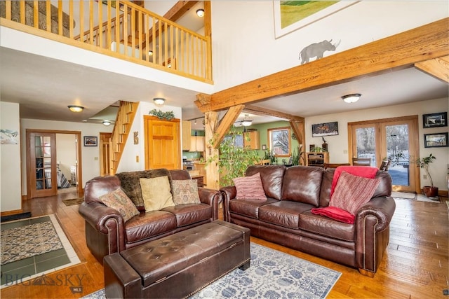 living room featuring hardwood / wood-style flooring, a towering ceiling, beam ceiling, and french doors