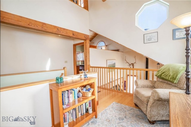 living area featuring beamed ceiling, a towering ceiling, and hardwood / wood-style floors