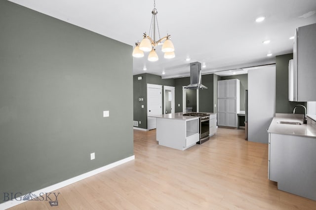 kitchen with a kitchen island, sink, hanging light fixtures, island exhaust hood, and stainless steel gas range