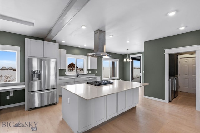 kitchen with stainless steel appliances, decorative light fixtures, a center island, and island range hood