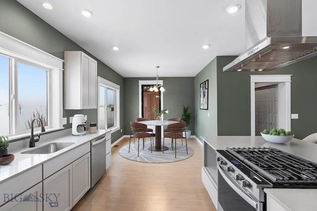 kitchen with pendant lighting, sink, stainless steel appliances, white cabinets, and island exhaust hood