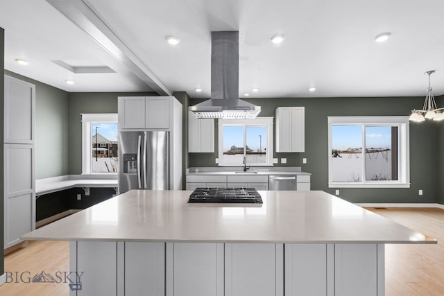 kitchen with a large island, pendant lighting, stainless steel appliances, island range hood, and light hardwood / wood-style floors