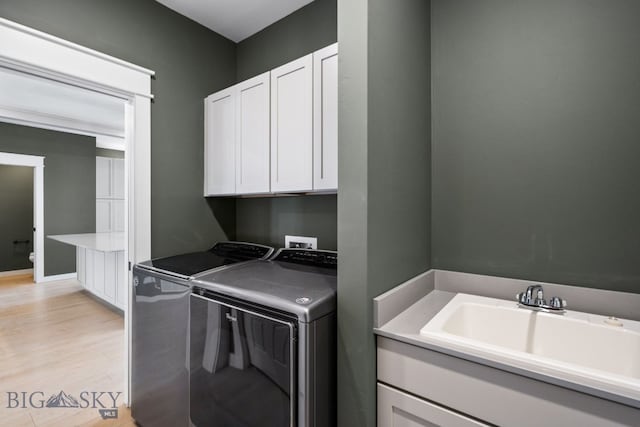 laundry area with cabinets, separate washer and dryer, sink, and light wood-type flooring