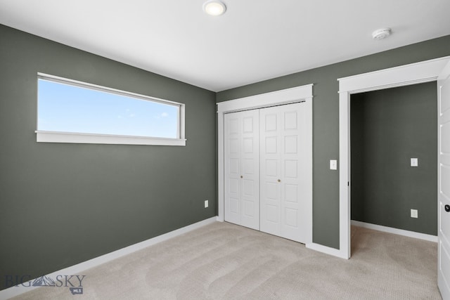 unfurnished bedroom featuring light carpet and a closet