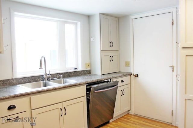 kitchen featuring light wood-type flooring, stainless steel dishwasher, and a sink