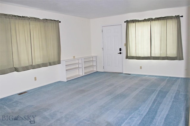 carpeted spare room featuring baseboards and visible vents
