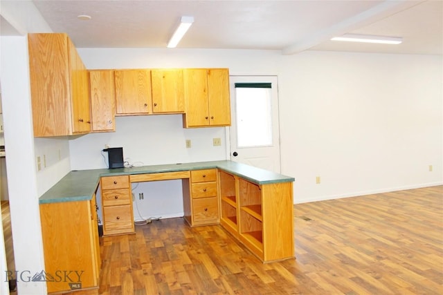 kitchen with open shelves, built in desk, dark countertops, dark wood-style floors, and a peninsula