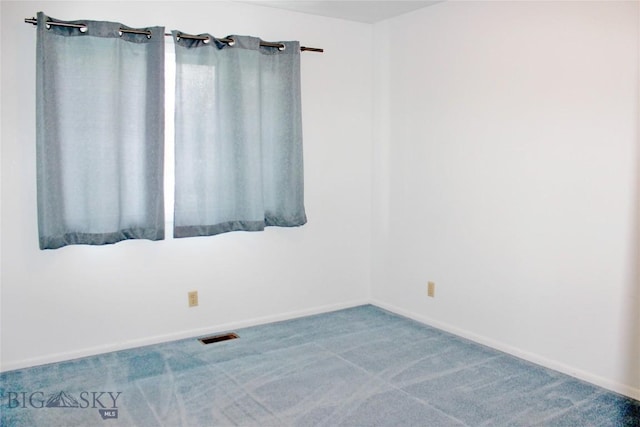 spare room featuring carpet flooring and baseboards