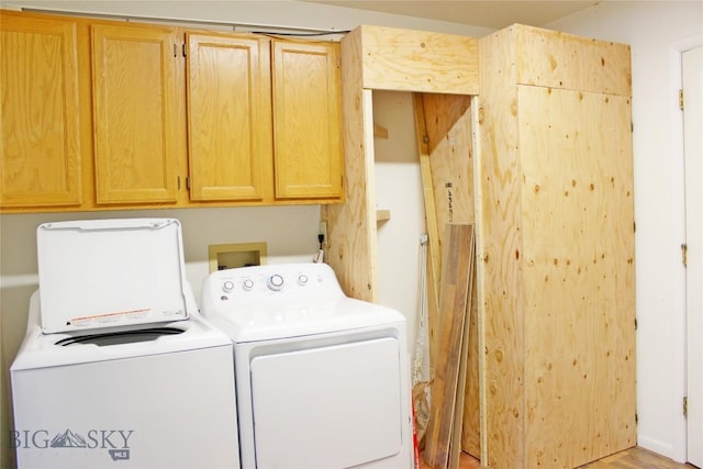 laundry area featuring light wood-style floors, washing machine and clothes dryer, and cabinet space