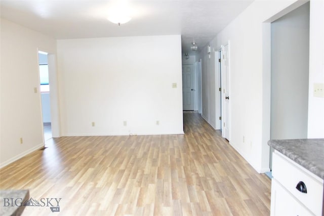 unfurnished room with baseboards and light wood-type flooring
