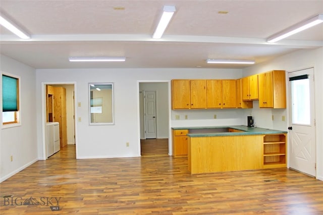 kitchen with independent washer and dryer, kitchen peninsula, and light hardwood / wood-style flooring