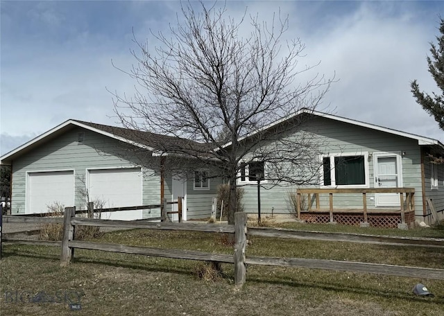 ranch-style home featuring driveway, an attached garage, and a fenced front yard