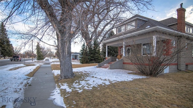 snow covered property featuring a porch and a lawn