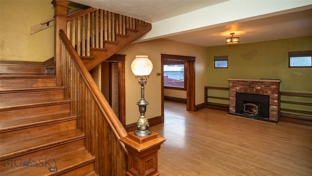 stairway with hardwood / wood-style floors and a fireplace