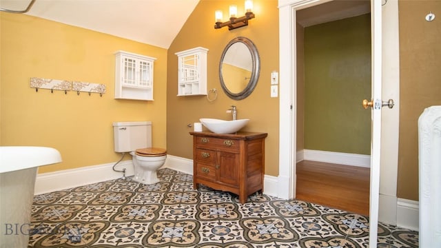 bathroom with lofted ceiling, tile patterned floors, toilet, and vanity