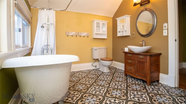 bathroom with tile patterned flooring, vanity, lofted ceiling, and toilet