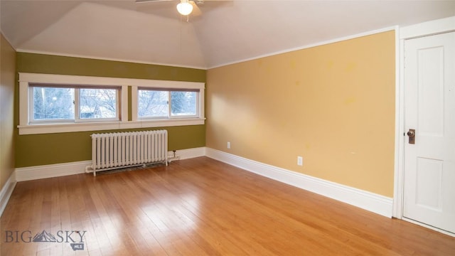 interior space with ceiling fan, hardwood / wood-style floors, radiator heating unit, ornamental molding, and vaulted ceiling