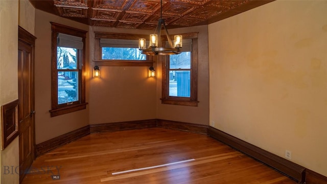 unfurnished dining area with wood-type flooring, an inviting chandelier, and baseboard heating