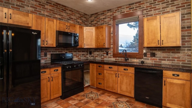 kitchen featuring brick wall, sink, dark stone countertops, and black appliances