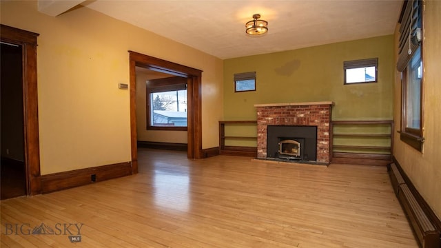 unfurnished living room with baseboard heating and light wood-type flooring