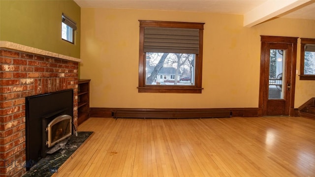 unfurnished living room with a brick fireplace, light hardwood / wood-style flooring, beamed ceiling, and baseboard heating