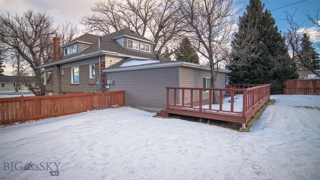 snow covered back of property featuring a wooden deck