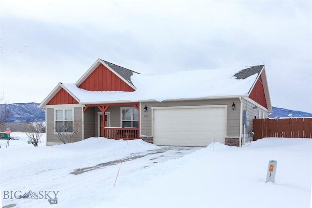 view of front of house featuring stone siding, board and batten siding, an attached garage, and fence