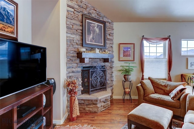 living room with a fireplace, baseboards, and wood finished floors