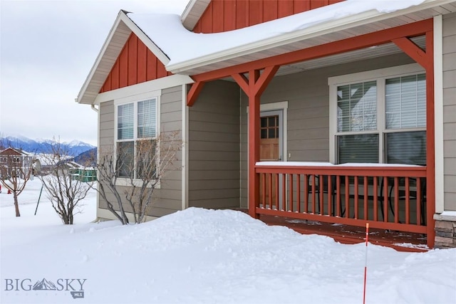 snow covered property entrance featuring a mountain view and covered porch