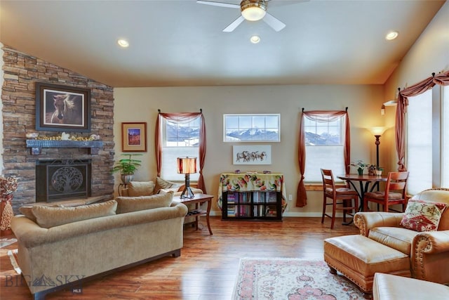 living room with a stone fireplace, recessed lighting, wood finished floors, a ceiling fan, and vaulted ceiling