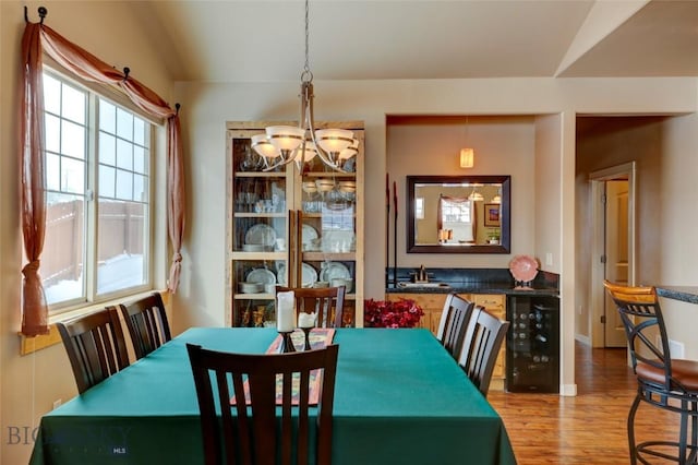 dining room with wine cooler, wood finished floors, and an inviting chandelier