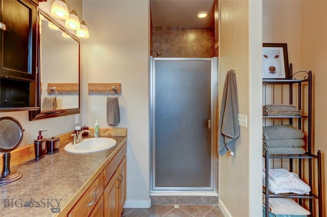 full bath with a shower stall, vanity, baseboards, and tile patterned floors