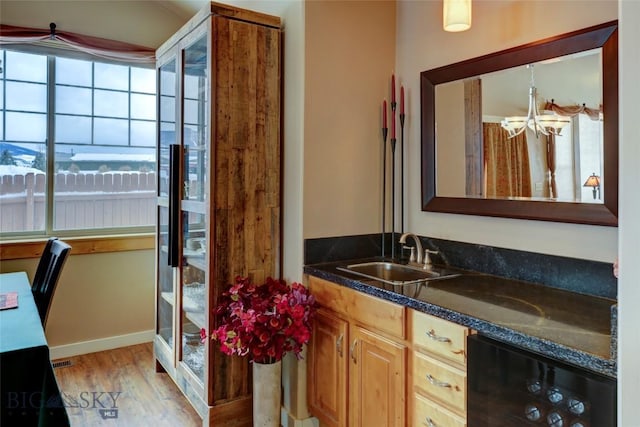 bathroom featuring a notable chandelier, beverage cooler, wood finished floors, vanity, and baseboards