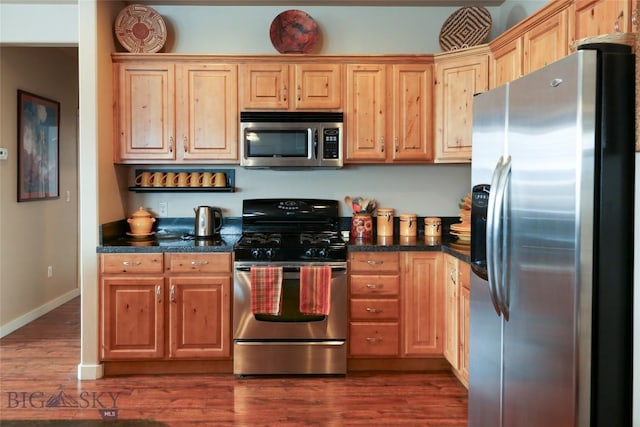 kitchen with appliances with stainless steel finishes, dark wood-style flooring, and baseboards