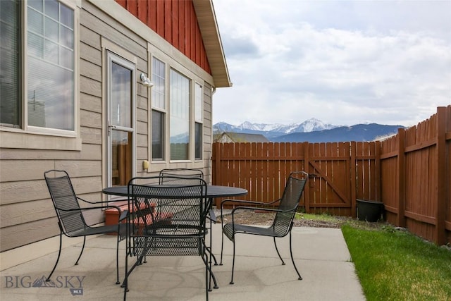 view of patio featuring outdoor dining area, fence, and a mountain view