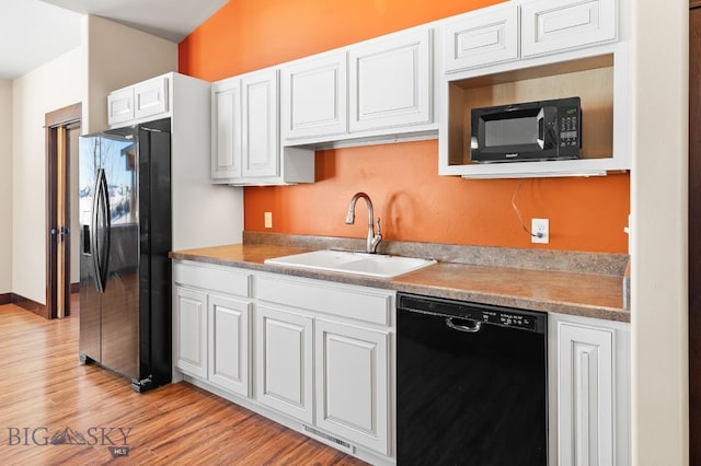 kitchen with white cabinetry, light wood-type flooring, sink, and black appliances