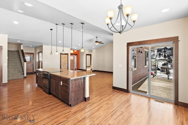 kitchen with hanging light fixtures, black range with electric stovetop, dark brown cabinets, and a center island