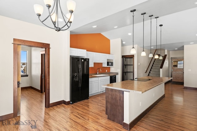 kitchen with white cabinetry, pendant lighting, a large island with sink, and black appliances