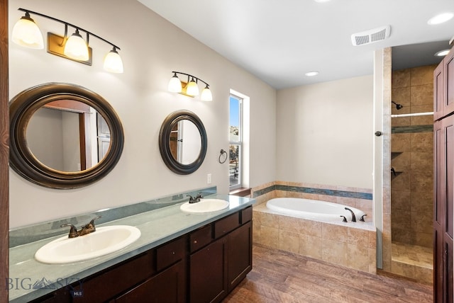 bathroom featuring wood-type flooring, shower with separate bathtub, and vanity