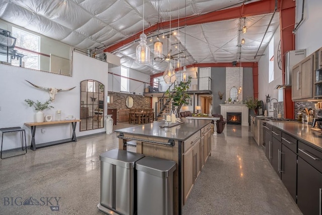 kitchen featuring hanging light fixtures, a high ceiling, a center island, and a large fireplace