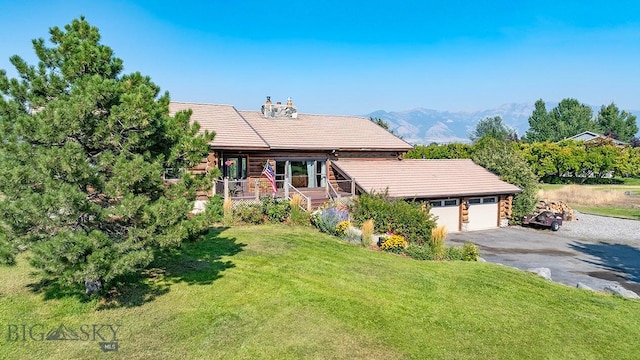 view of front facade with a garage, a mountain view, covered porch, and a front yard