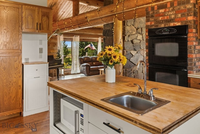 kitchen with double oven, butcher block counters, sink, white cabinets, and hardwood / wood-style flooring