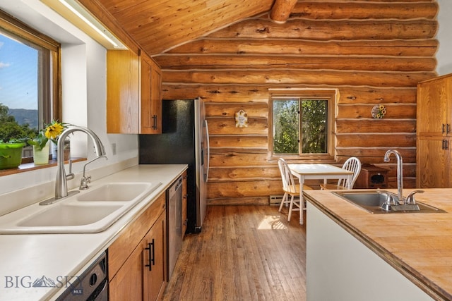 kitchen with vaulted ceiling, sink, and rustic walls