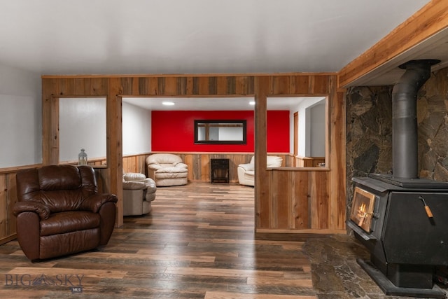 living room featuring dark hardwood / wood-style floors, a wood stove, and wooden walls