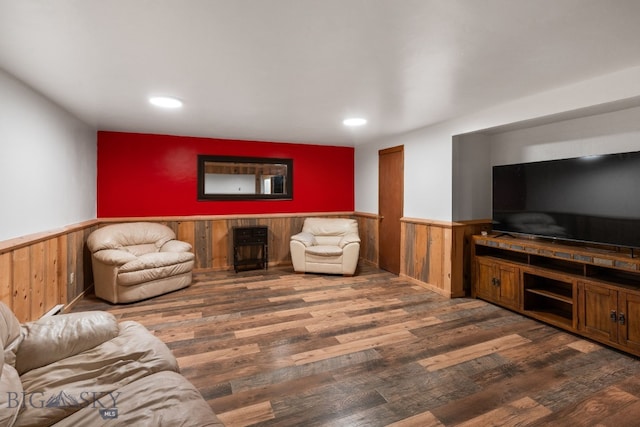 living room featuring dark wood-type flooring and wooden walls