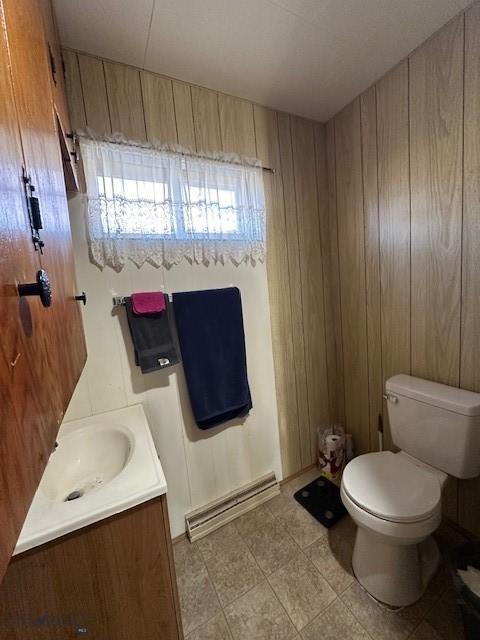 bathroom with vanity, toilet, and wood walls