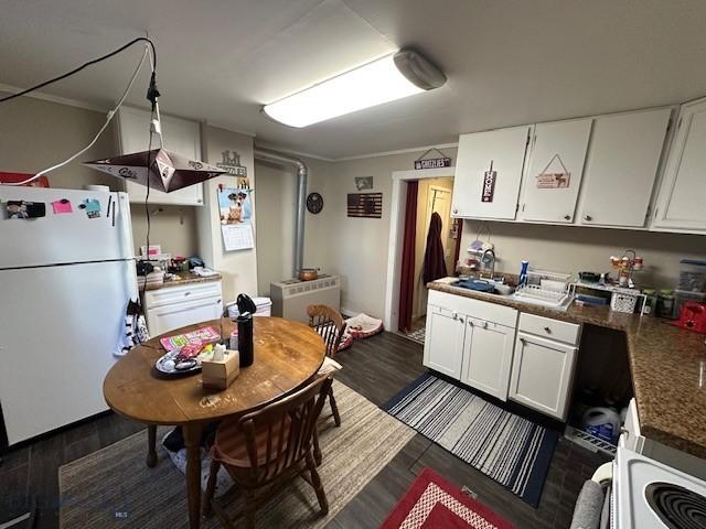 kitchen with dark hardwood / wood-style flooring, crown molding, white cabinets, and white appliances